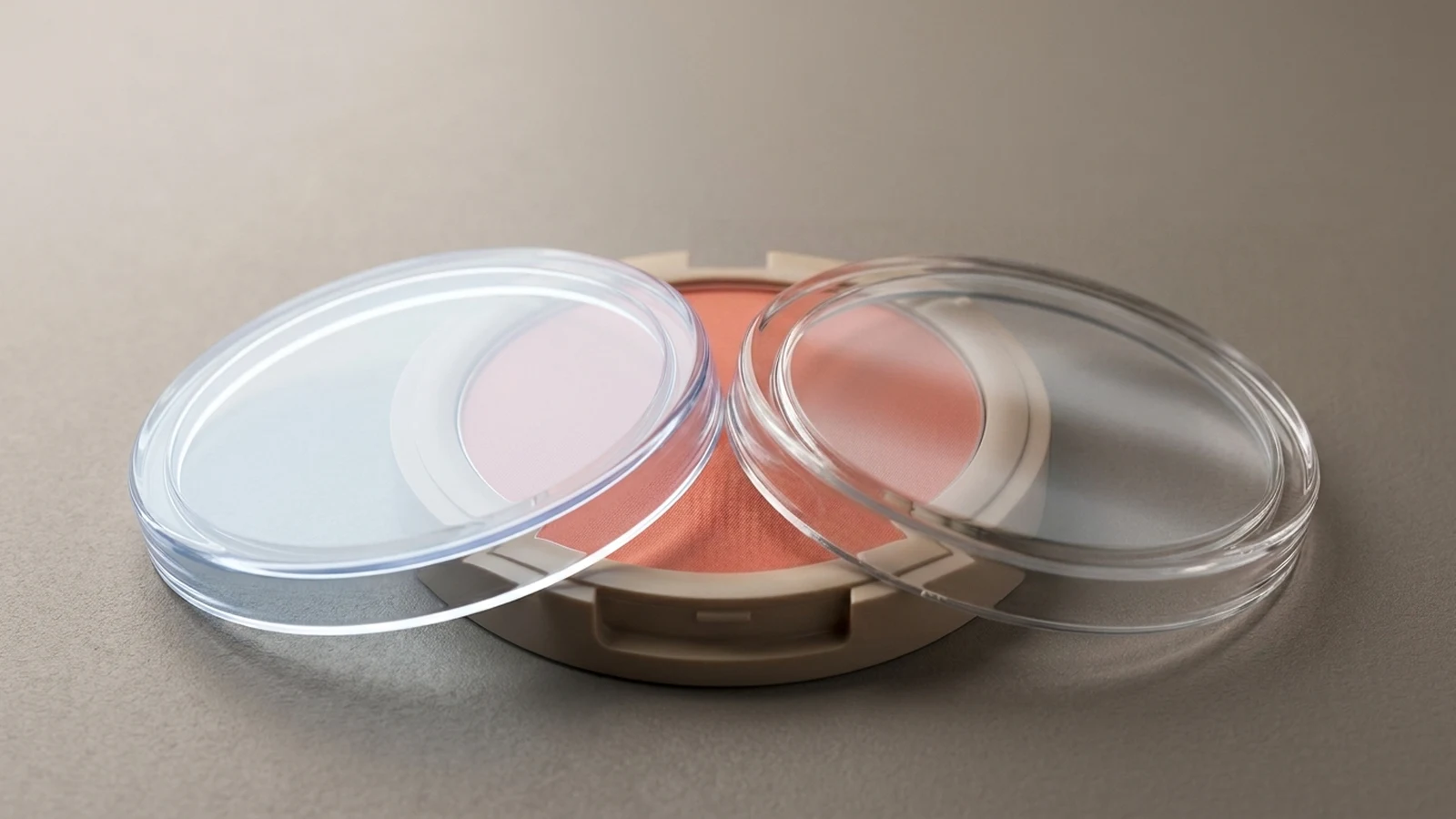 Comparison between AS and PMMA acrylic clear compact powder case lids placed over warm-toned pressed powder